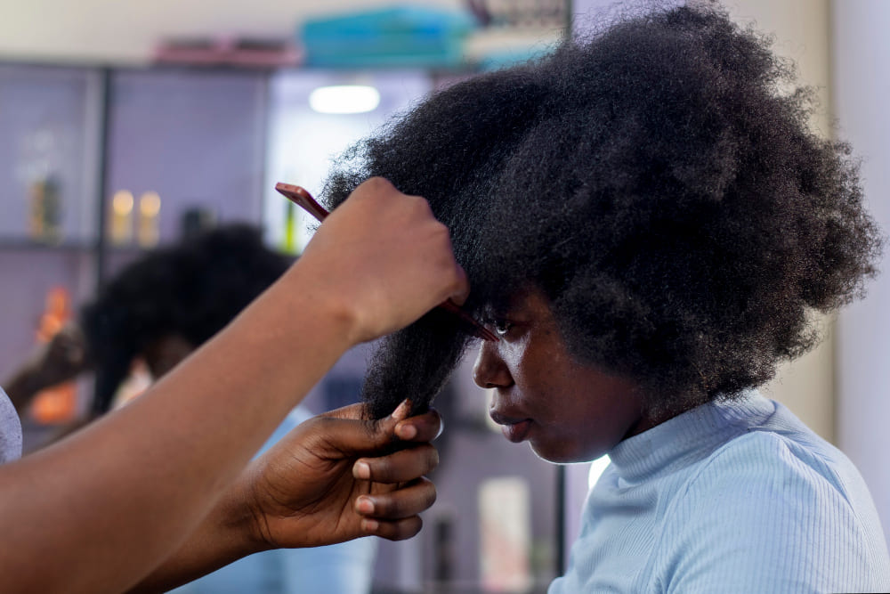 Mulher negra tratanto o cabelo de outra mulher